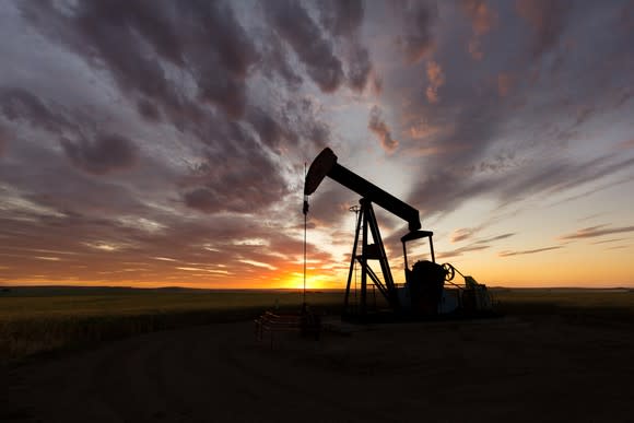 An oil pump with the sun setting in the background.