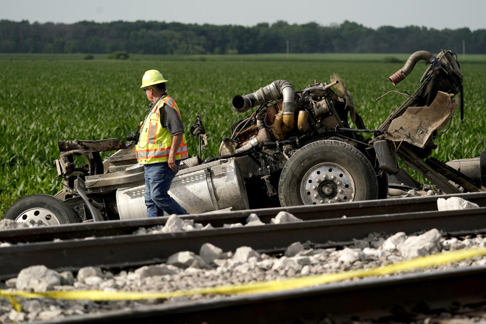 A worker looks over a dump truck that collided with an Amtrak train, causing it to derail Monday, June 27, 2022, near Mendon, Mo. (AP Photo/Charlie Riedel)