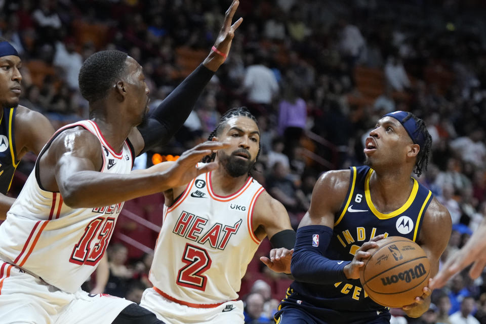 Indiana Pacers guard Buddy Hield, right, looks for an opening past Miami Heat center Bam Adebayo (13) and guard Gabe Vincent (2) during the first half of an NBA basketball game, Wednesday, Feb. 8, 2023, in Miami. (AP Photo/Wilfredo Lee)
