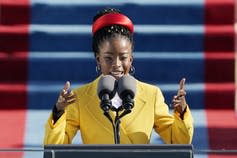 Amanda Gorman, in a yellow coat, reads a poem at the inauguration.