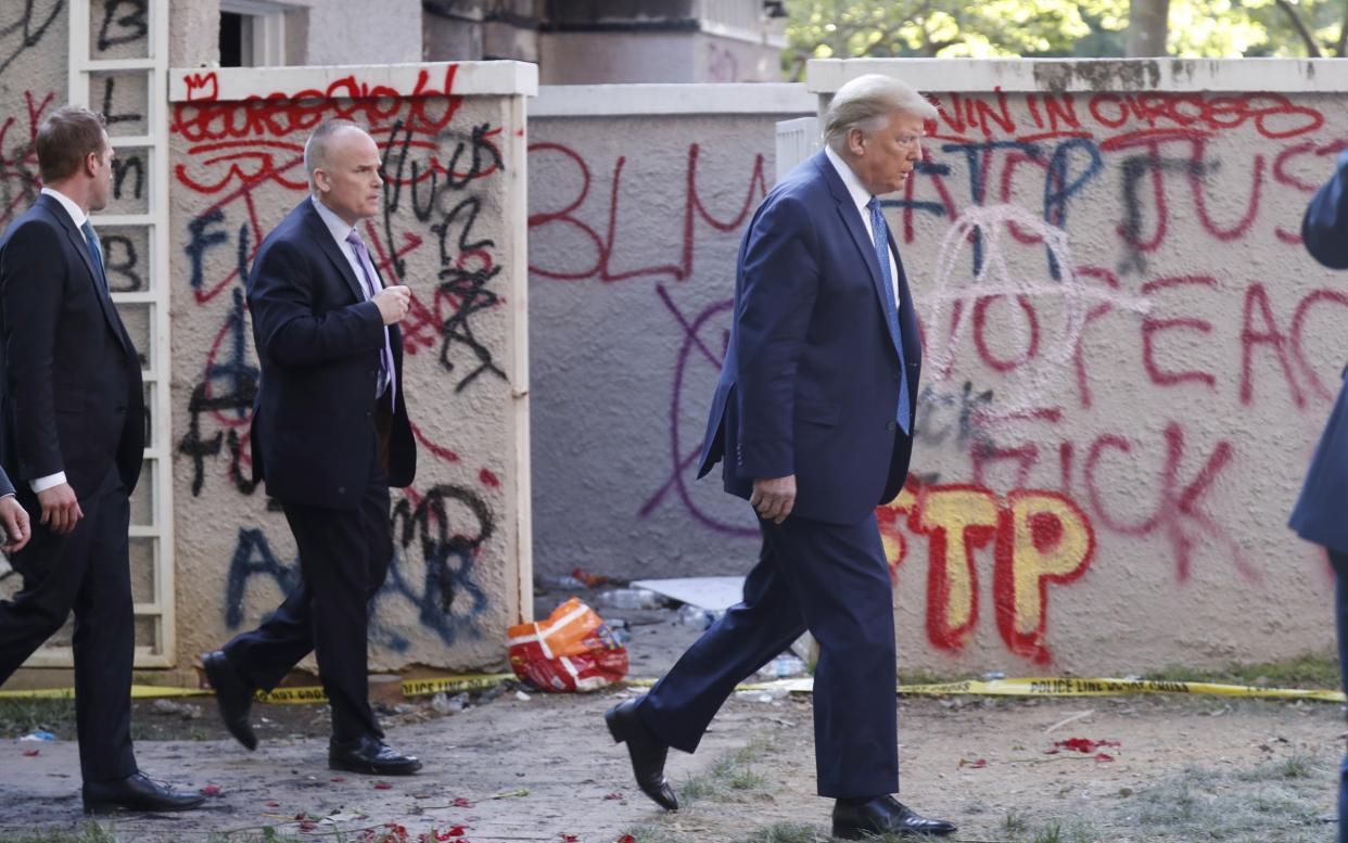 Donald Trump walks past graffiti as he heads from the White House to St John Episcopal Church after threatening to deploy the US military to crush protests over the killing of George Floyd: EPA