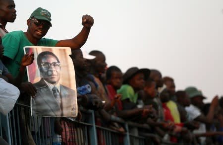 A mourner holds a poster of Robert Mugabe during the viewing of his body as it lies in state at the Rufaro stadium, in Mbare