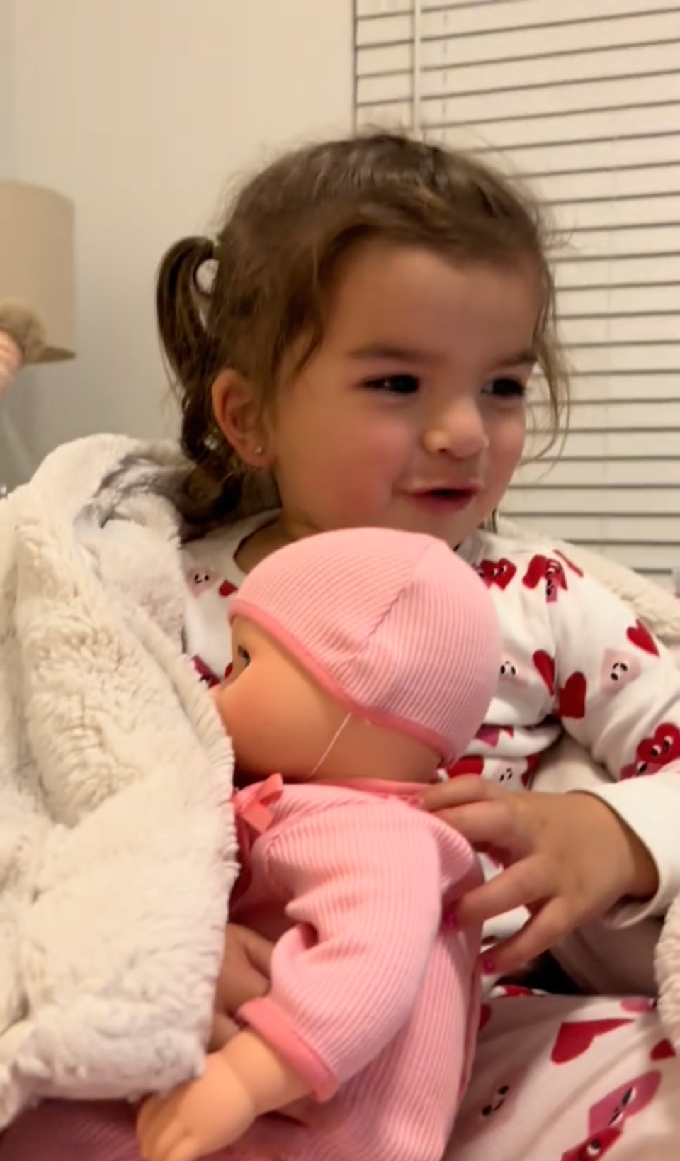 Baby Emma with her baby doll, watching the adventure she had at work (TikTok)