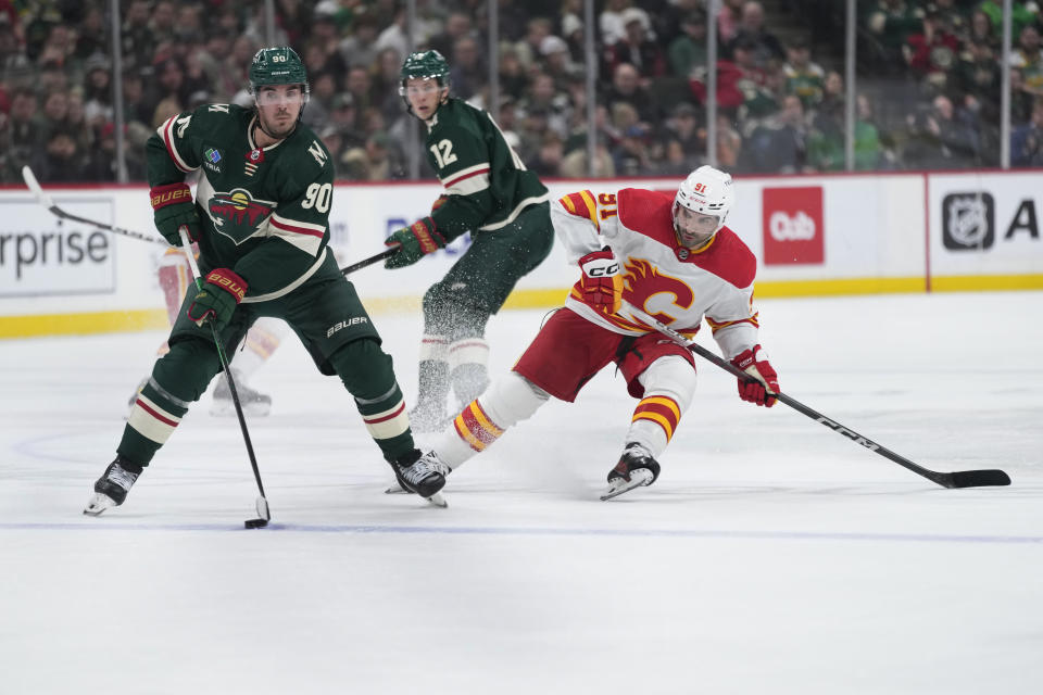 Minnesota Wild left wing Marcus Johansson (90) skates with the puck as Calgary Flames center Nazem Kadri (91) follows during the first period of an NHL hockey game Tuesday, Jan. 2, 2024, in St. Paul, Minn. (AP Photo/Abbie Parr)