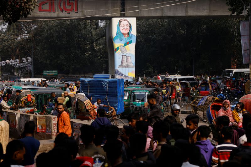 People are stuck in traffic alongside a metro rail pillar with a graffiti of Sheikh Hasina, the Prime Minister of Bangladesh in Dhaka