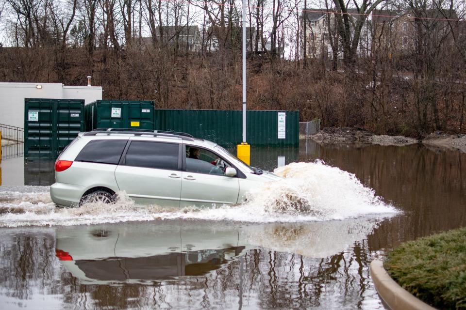 A minivan plows through the flooded rear parking lot of a shopping center off of Branch Avenue in Providence on Saturday.