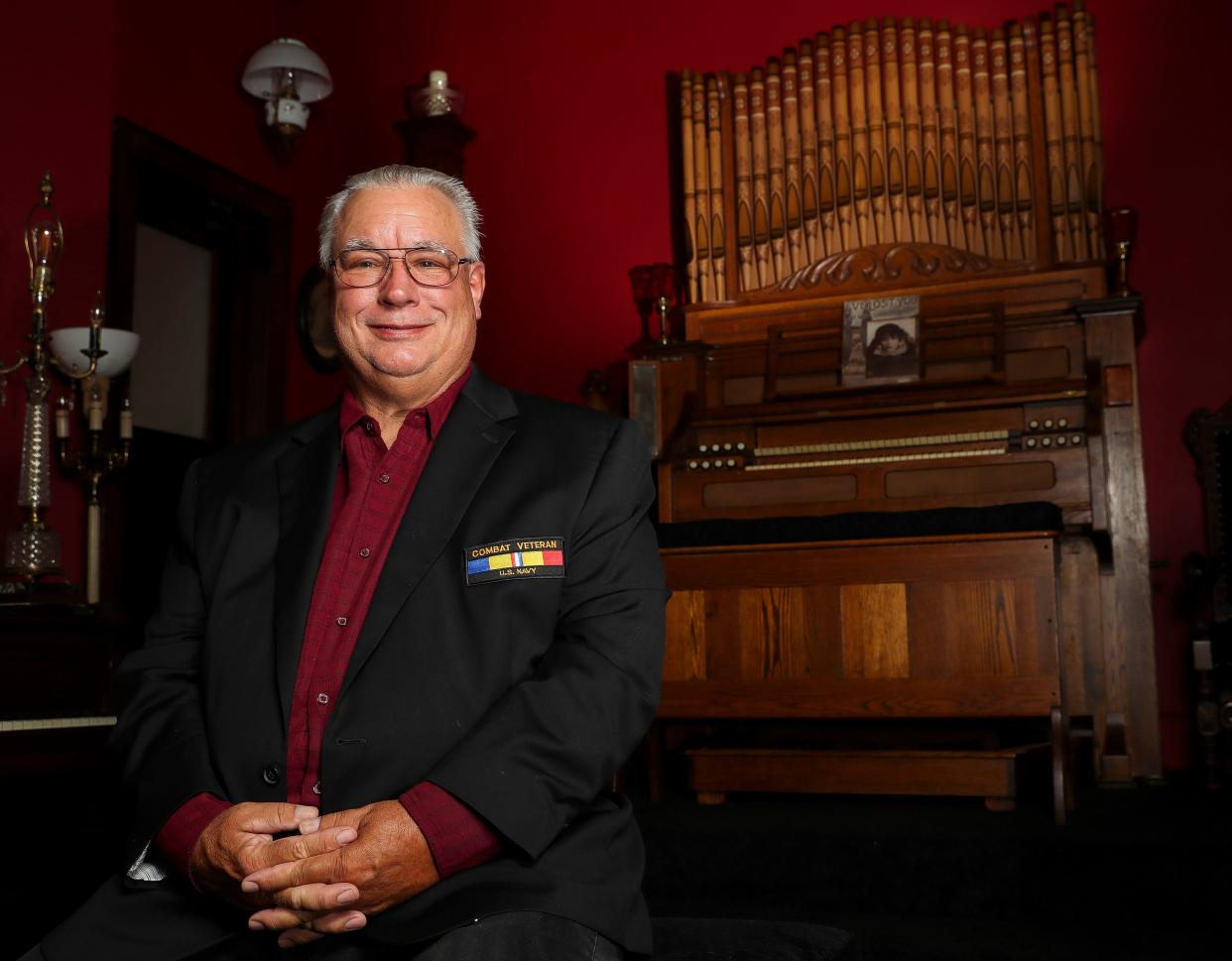 Michael Kennelly poses for a portrait in front of an antique pump organ on September 8, 2023 at the former Grace Baptist Church in Marshfield. Kennelly recently purchased the property in order to have more space for his vast collection of pump organs and other antiques.