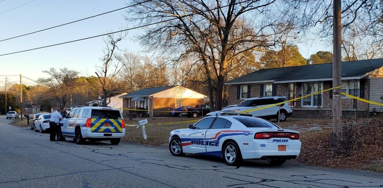 Police vehicles and crime scene tape surround a home on Ryan Street where a woman was shot and killed Monday in a domestic disturbance.