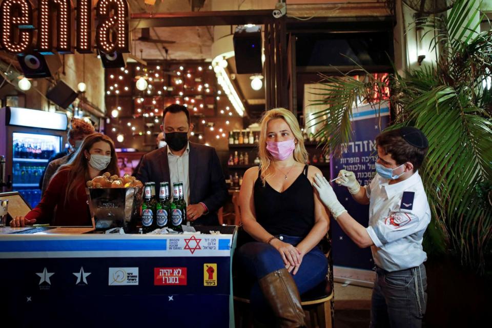 PHOTO: A woman receives a COVID-19 vaccine dose as part of a Tel Aviv municipality initiative offering a free non-alcoholic drink at a bar to residents getting the shot, in Tel Aviv, Israel on Feb. 18, 2021. (Corinna Kern/Reuters)