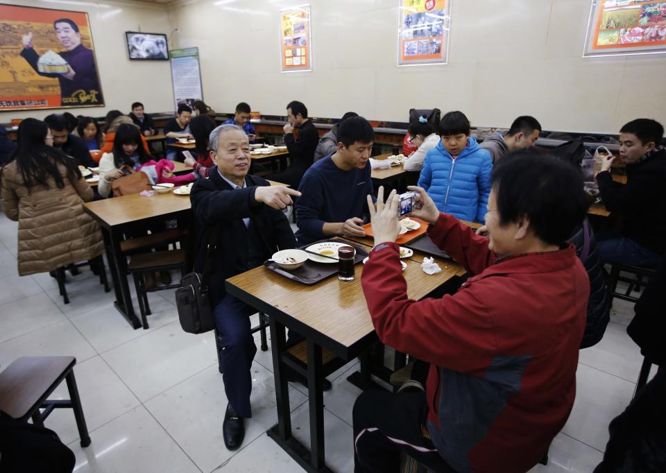 A diner seated at the table where Chinese President Xi sat at when he visited, poses for a photo at the Qing-Feng steamed buns restaurant in Beijing