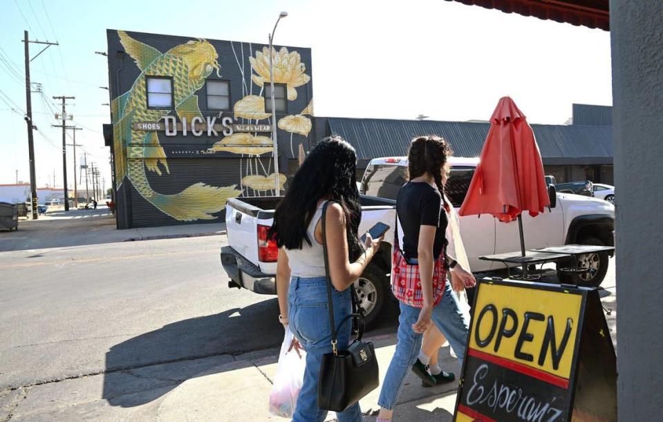 Pedestrians visiting Chinatown pass Esperanza’s Cocina offering Mexican food at the end of China Alley, with a giant koi mural seen across the street at the historic Dick’s Menswear building, photographed Saturday, Oct. 21, 2023 in downtown Fresno.