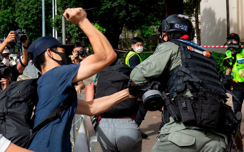 A protester (L) using a sharp object against a police officer (R) who is trying to detain a man (C) during a rally against a new national security law -  ALASTAIR PIKE/AFP