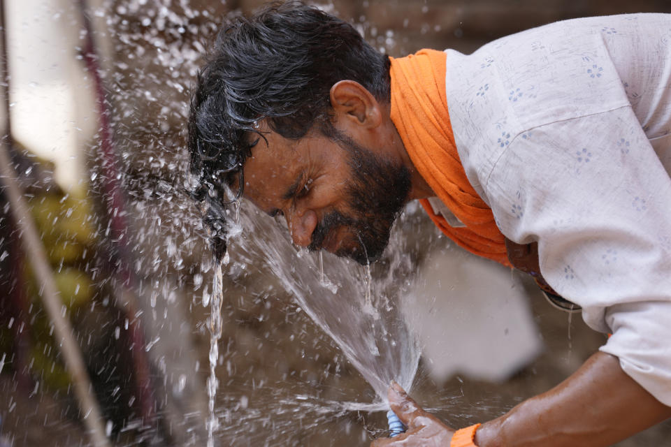 Un hombre se moja el rostro con agua de un grifo en la calle para refrescarse en un día de mucho calor en Lucknow, India, el 27 de mayo de 2024. (AP Foto/Rajesh Kumar Singh)
