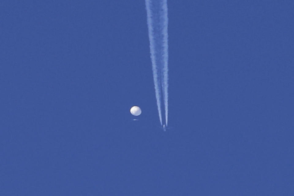 An airplane flies below a large balloon as it drifts above the Kingstown, N.C. (Brian Branch via AP)