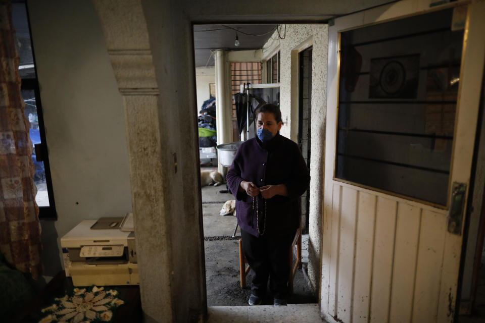 Leticia Pinera Santana stands outside as she leads prayers for her father-in-law, Manuel Briseno Espino, 78, who died from complications due to COVID-19, at the family's home in the Iztapalapa district of Mexico City, Wednesday, April 22, 2020. Due to social distancing restrictions, the seven family members from three generations who lived with Briseno marked his passing with quiet prayers at home, unable to invite his many friends or other relatives, or to bury him in the cemetery plot with his late wife of 49 years, Consuelo Garcia Rodriguez. (AP Photo/Rebecca Blackwell)