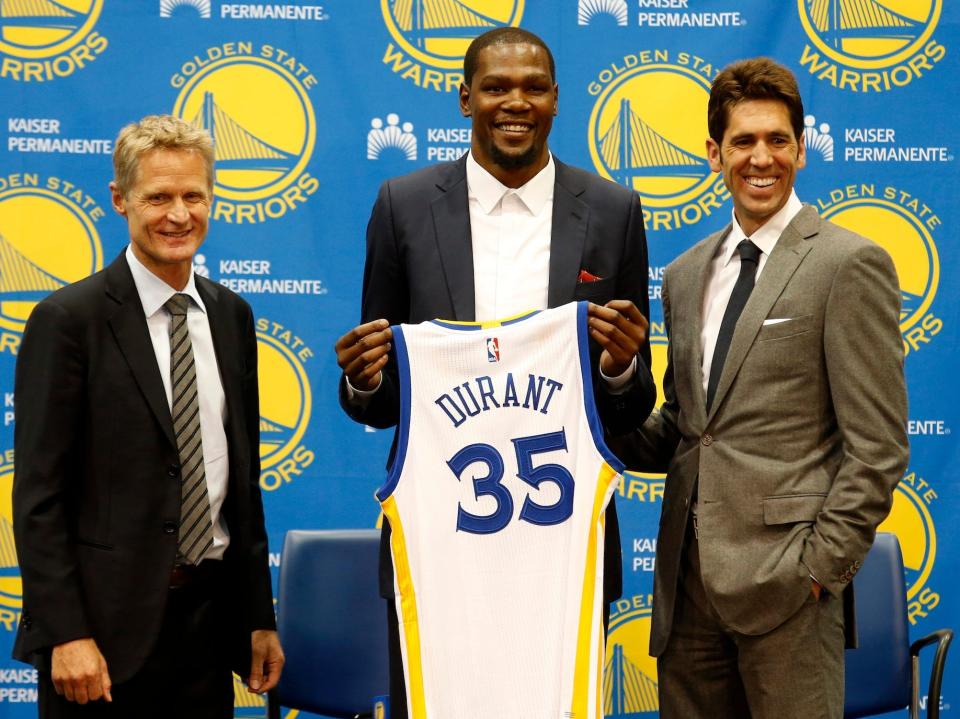 Kevin Durant poses with a Warriors jersey between Steve Kerr and Bob Myers in 2016.