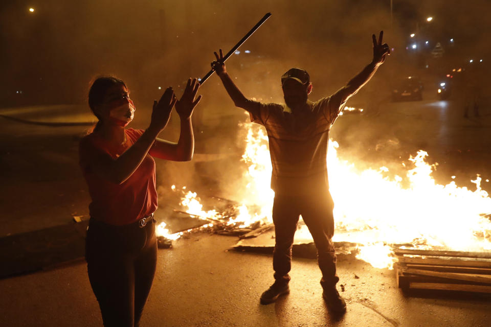 Anti-government protesters shout slogans as they block a highway by burned tires and woods, during a protest against the political leadership they blame for the economic and financial crisis, in front of the government house, in downtown Beirut, Lebanon, Thursday, June 11, 2020. (AP Photo/Hussein Malla)