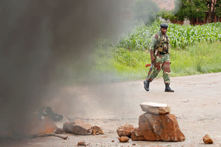 A soldier walks past a burning barricade in Harare, Zimbabwe, January 15, 2019. REUTERS/Philimon Bulawayo