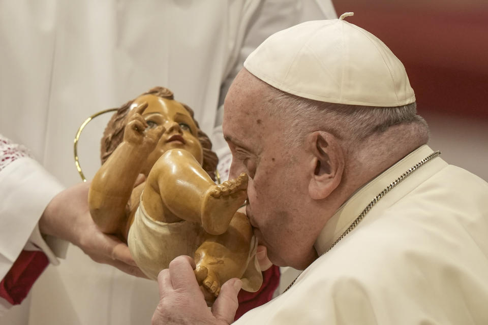 Pope Francis kisses a model of baby Jesus as he presides over an Epiphany mass in St.Peter's Basilica, at the Vatican, Saturday, Jan. 6, 2024. (AP Photo/Andrew Medichini)