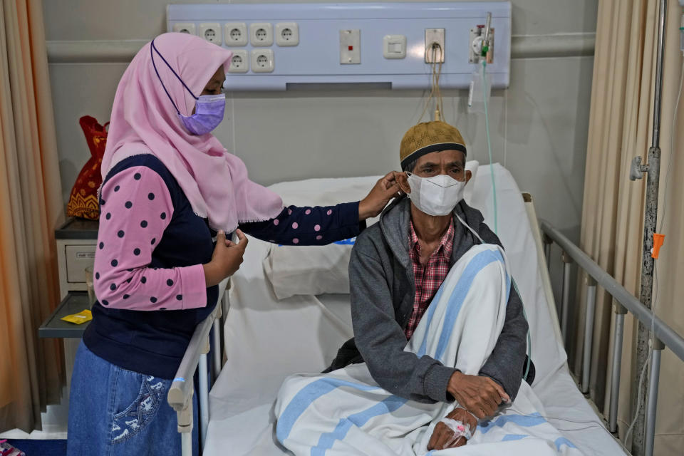 Misnar, right, a street vendor who suffers from pneumonia, sits on his bed as his daughter Siti Nurzanah adjusts his mask at Persahabatan Hospital in Jakarta, Indonesia, on Sept. 22, 2023. Pollution is causing respiratory illnesses and deaths to rise in Indonesia's island of Java, including the capital, Jakarta. Data gathered by IQAir, a Swiss air technology company, regularly ranks Jakarta as one of the most polluted cities in the world. Blue skies are a rare sight and the air often smells like fuel or heavy smoke.(AP Photo/Achmad Ibrahim)