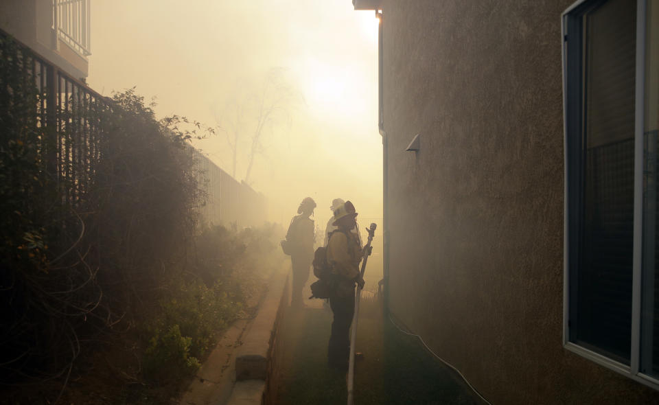 Firefighters are obscured by smoke from an advancing wildfire Friday, Oct. 11, 2019, in Porter Ranch, Calif. (AP Photo/Marcio Jose Sanchez)