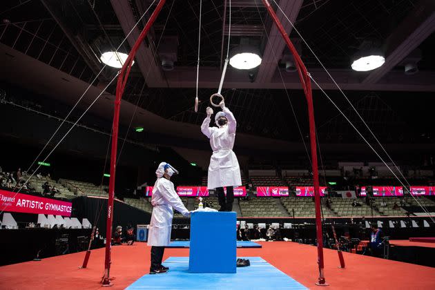 Staff members disinfect the rings as a preventive measure against the coronavirus during the Artistic Gymnastics World Championships at the Kitakyushu City Gymnasium in Japan, on Oct. 20. (Photo: PHILIP FONG/AFP via Getty Images)