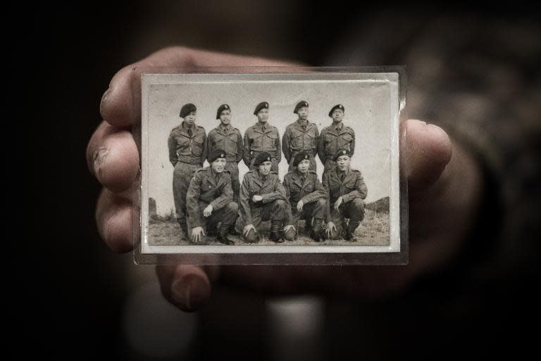 Leung Wai-sang, 70, who was a driver in Hong Kong's colonial-era transport corps in the 1960s, shows a photo of himself and a group of servicemen