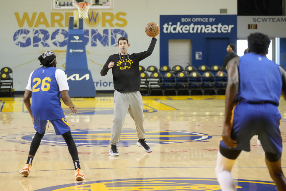 Santa Cruz Warriors coach Nicholas Kerr, middle, throws a ball toward players during the team's basketball practice in Santa Cruz, Calif., Friday, Jan. 12, 2024. Each day, Kerr strives to find a balance between fun and fire while leading Golden State's developmental G League team minus all the big stars - like Stephen Curry - his famous father, Steve Kerr, gets to work with every day. (AP Photo/Jeff Chiu)