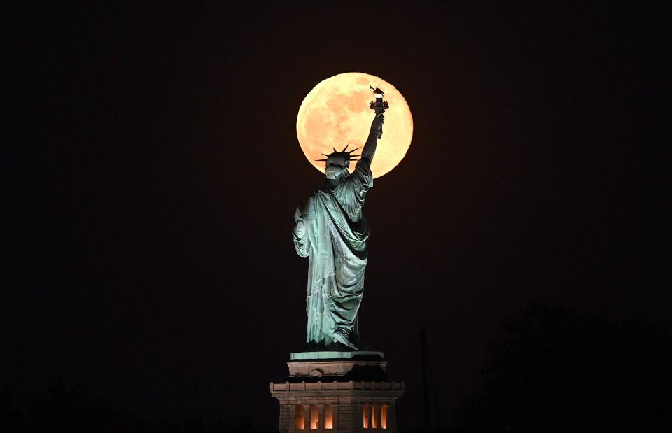 May's full Moon, known as the full flower moon, rises behind the Statue of Liberty on May 7, 2020, in New York City.