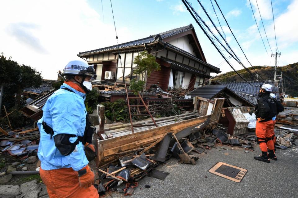 Firefighters inspect collapsed wooden houses in Wajima, Ishikawa prefecture (AFP via Getty Images)