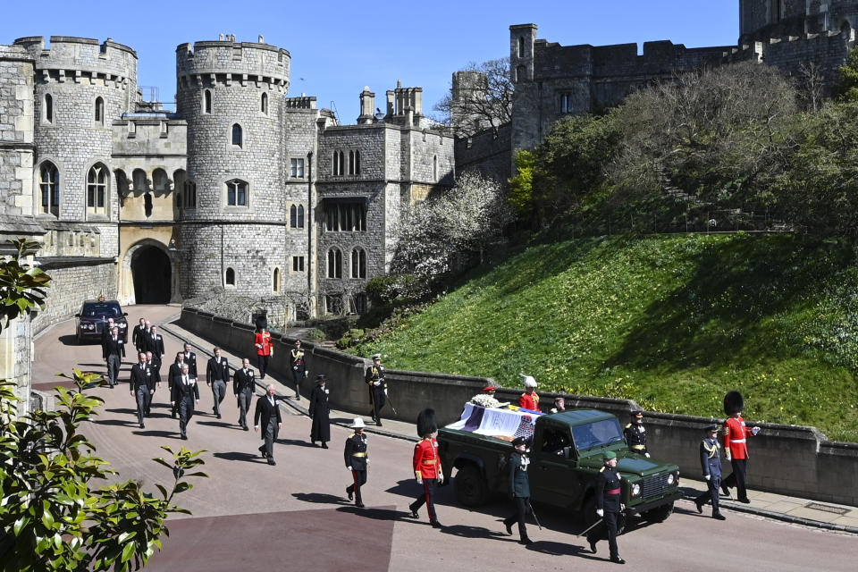 Britain's Prince Charles, from front left, Princess Anne, Prince Andrew. Prince Edward, Prince William, Peter Phillips, Prince Harry, Earl of Snowdon, Tim Laurence and Queen Elizabeth II, in car at rear, follow the coffin as it makes it's way past the Round Tower during the funeral of Britain's Prince Philip inside Windsor Castle in Windsor, England Saturday April 17, 2021. (Leon Neal/Pool via AP)