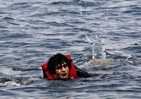 An exhausted Syrian refugee swims towards the Greek island of Lesbos after jumping off an overcrowded dinghy whille crossing part of the Aegean Sea from Turkey to Lesbos September 23, 2015. REUTERS/Yannis Behrakis