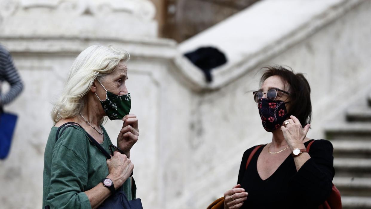 Zwei Frauen mit Masken stehen vor einer Treppe in Rom.