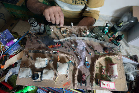 Palestinian diorama artist Majdi Abu Taqeya works on miniature figures he carves from remnants of Israeli ammunition collected from the scenes of border protests along the Israel-Gaza border, in the central Gaza Strip March 11, 2019. Picture taken March 11, 2019. REUTERS/Ibraheem Abu Mustafa