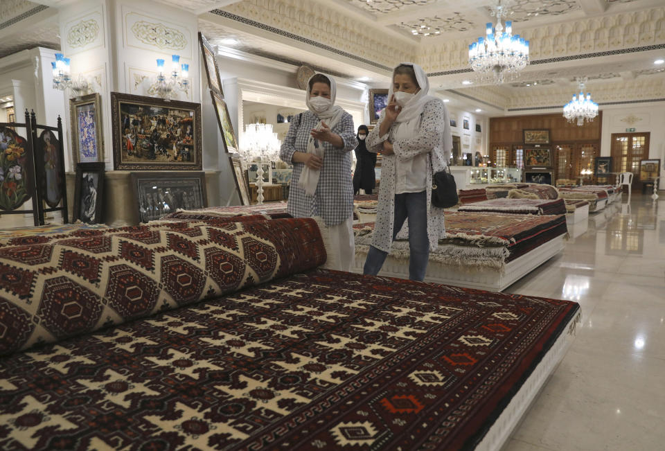 Customers look at rugs at a hand crafts store at Iran Mall shopping center in Tehran, Iran, Wednesday, June 9, 2021. The West considers Iran's nuclear program and Mideast tensions as the most important issues facing Tehran, but those living in the Islamic Republic repeatedly point to the economy as the major issue facing it ahead of its June 18 presidential election. (AP Photo/Vahid Salemi)