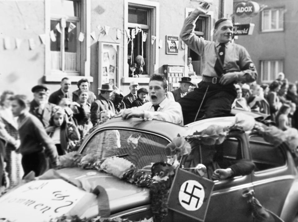 <i>A Nazi Party member rides in the back of a Volkswagen during a parade in Germany circa 1935.</i>