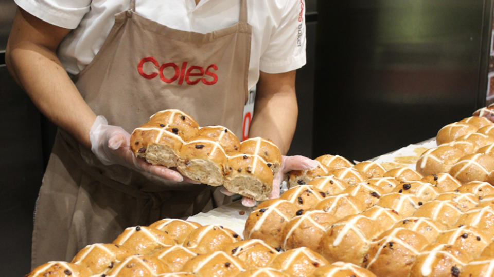 A baker holds six hot cross buns released on Boxing Day in Coles. 