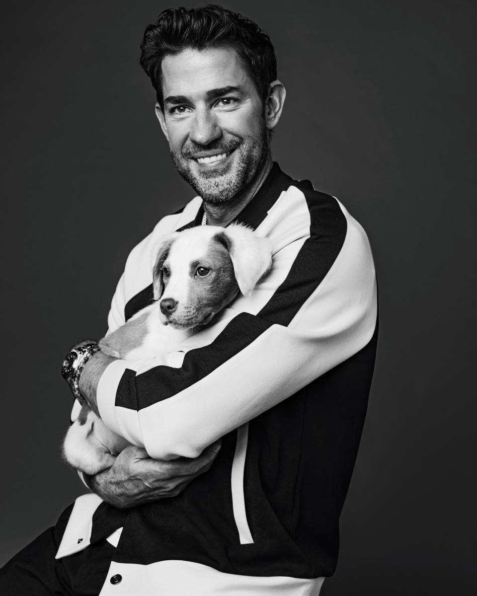 Man in a striped shirt holding a puppy against a neutral background