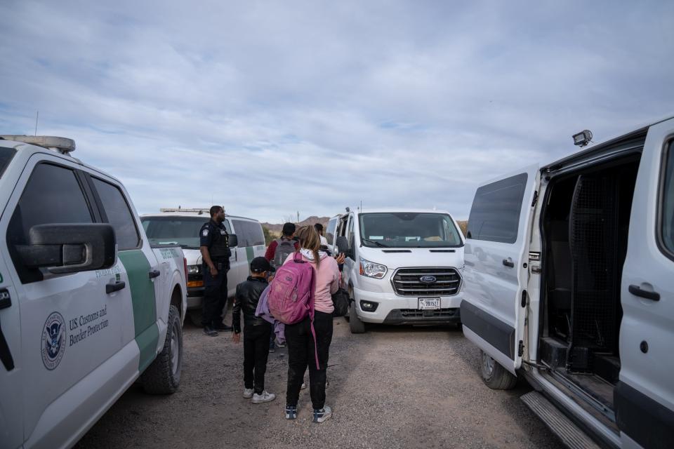 Migrants and asylum seekers are guided into vans to be transported for processing by U.S. Border Patrol agents in Organ Pipe Cactus National Monument along the U.S.-Mexico border about a mile west of Lukeville, Ariz., on Dec. 4, 2023. The Lukeville Port of Entry was closed indefinitely by officials Dec. 4.