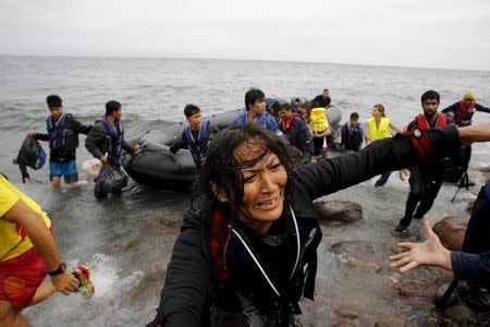 An exhausted Afghan migrant frantically looks for her children as she arrives on the Greek island of Lesbos in an overcrowded dinghy after crossing a part of the Aegean Sea from the Turkish coast September 22, 2015. REUTERS/Yannis Behrakis - RTX1RURY