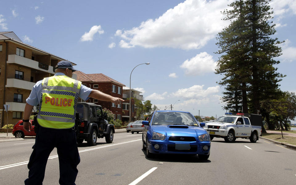 Police officer pulls over blue car. Source: AP