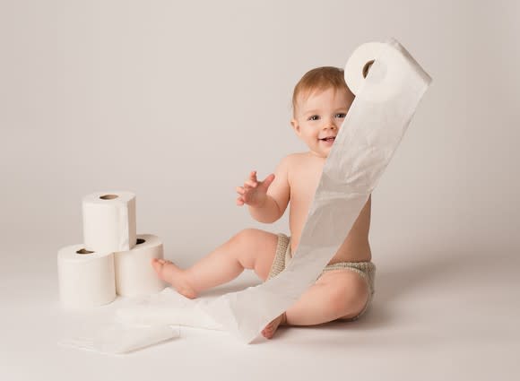 A baby plays with rolls of toilet paper.