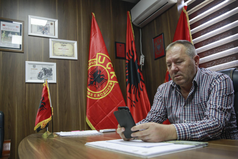 Hysni Gucati head of the War Veterans Organization of the Kosovo Liberation Army looks at a photo of his co-fighter former Kosovo Liberation Army commander Salih Mustafa after news of his arrest, during an interview with The Associated Press, in Pristina, Thursday, Sept. 24, 2020. A special international court said Thursday that a former commander of the separatist fighters in Kosovo's 1998-1999 war has been arrested as part of a war crimes and crimes against humanity probe stemming from the conflict with Serbia. (AP Photo/Visar Kryeziu)