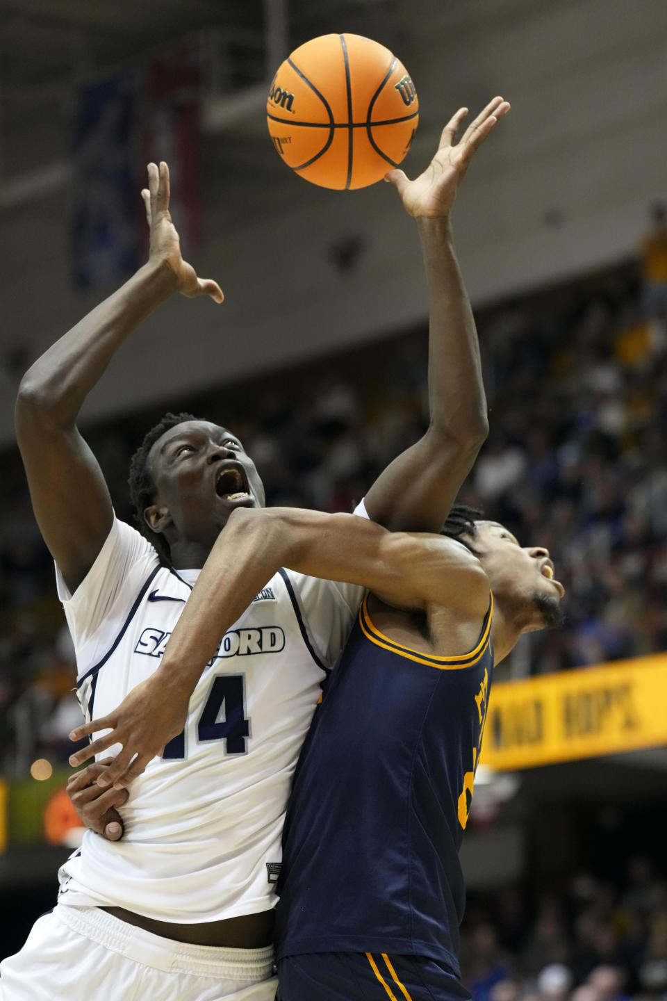 FILE - Samford forward Achor Achor (14) leaps to recover control of the ball as East Tennessee State forward Jaden Seymour (22) bumps him from the side during an NCAA college basketball championship game for the Southern Conference tournament, Monday, March 11, 2024, in Asheville, N.C. Samford has a chance to make some noise this week if Achor performs as well as he did in the Southern Conference Tournament. (AP Photo/Kathy Kmonicek, File)