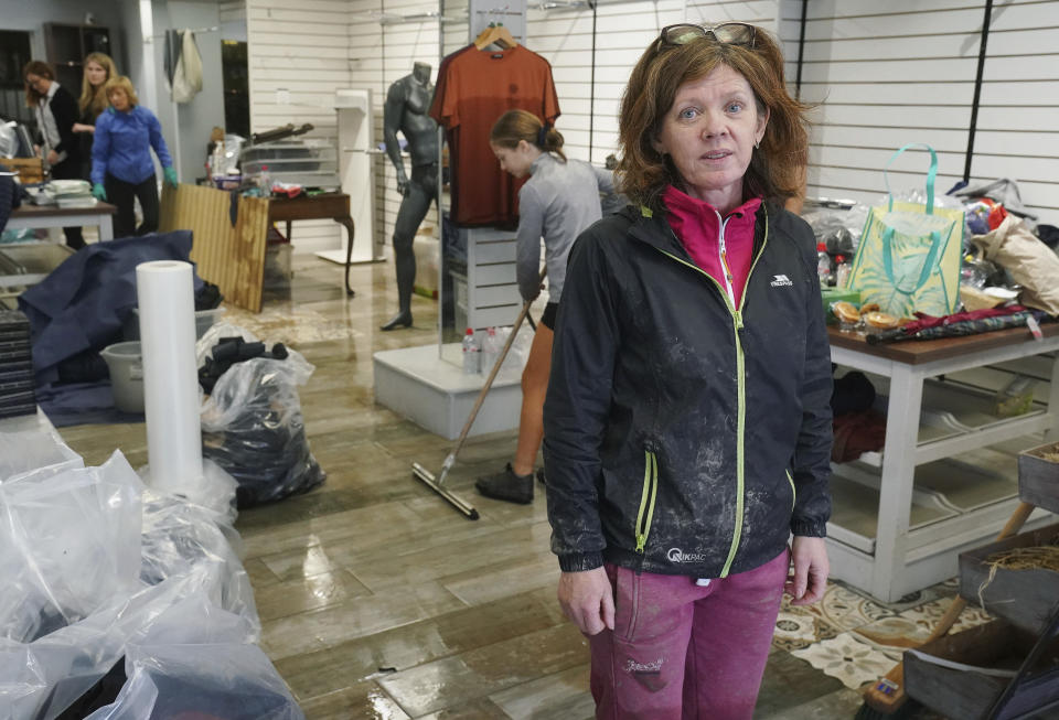 Sinead Morrissey, owner of Bertelli Menswear on Main Street, cleans up her shop which was badly damaged as Storm Babet, the second named storm of the season swept in, in Midleton, Co Cork, Ireland, Thursday Oct. 19, 2023. Hundreds of people are being evacuated from their homes and schools have closed in parts of Scotland, as much of northern Europe braces for stormy weather, heavy rain and gale-force winds from the east. (Brian Lawless/PA via AP)