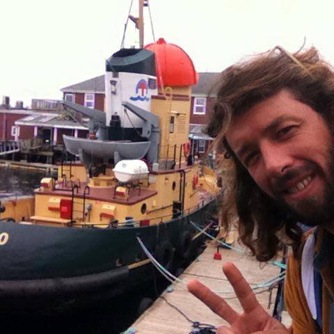 Sean McKinnon poses in front of a boat while making a peace symbol with his hand in 2016. 