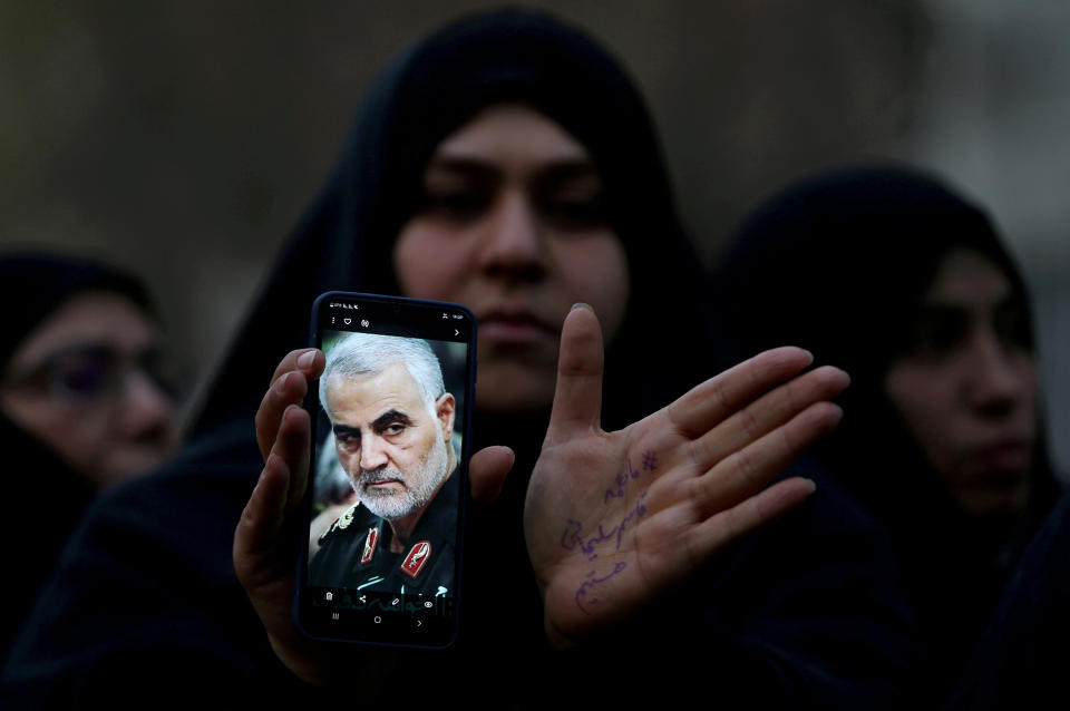 An Iranian woman shows a photo of the late Iranian Major-General Qassem Soleimani