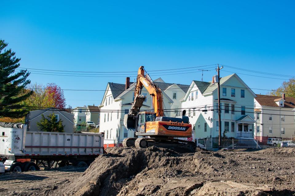 An excavator dumps dirt into the back of a semi-trailer on Nov. 3, 2023, as works begins on the construction of four 5-story apartment buildings on Gano and Power streets in Providence's Fox Point neighborhood.