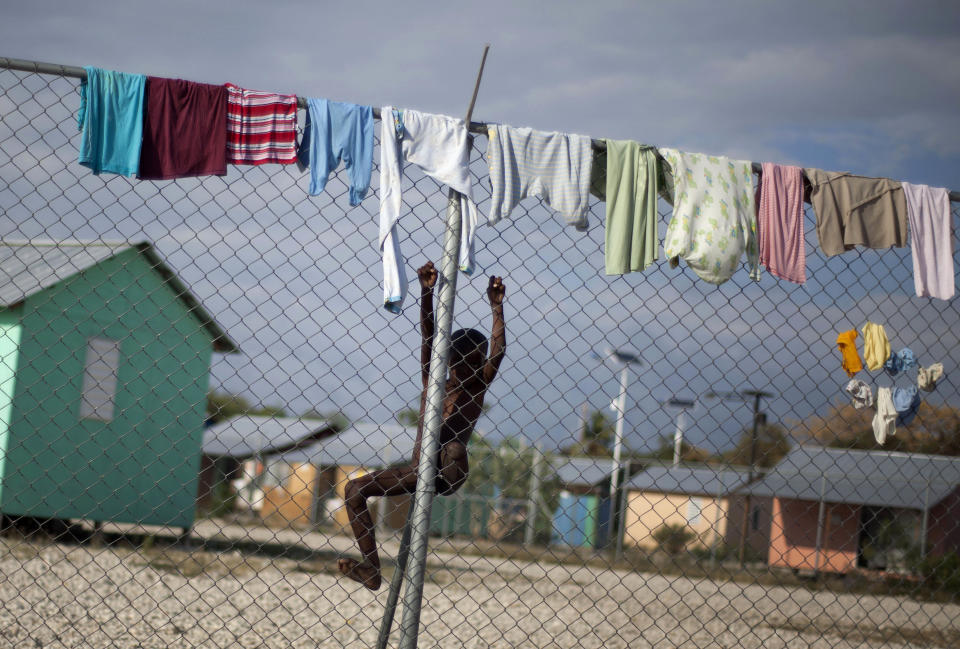 In this picture taken on Feb. 12, 2012, a child whose leg whose right leg was amputated due to an injury suffered in the 2010 earthquake, climbs a fence to get to his clothes hanging out to dry at La Piste camp in Port-au-Prince, Haiti. While more than a million people displaced by the 2010 quake ended up in post-apocalyptic-like tent cities, some of the homeless people with disabilities landed in the near-model community of La Piste, a settlement of plywood shelters along tidy gravel lanes. However, the rare respite for the estimated 500-plus people living at the camp is coming to an end as the government moves to reclaim the land. (AP Photo/Ramon Espinosa)