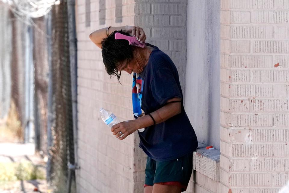 A person tries to cool off in the shade as temperatures are expected to hit 116 on July 18, 2023, in Phoenix.